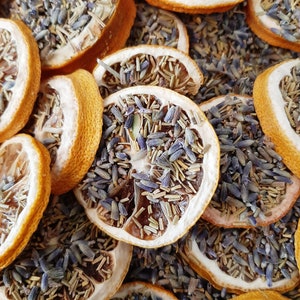 May include: Dried lemon slices with lavender buds and stems. The lemon slices are a light yellow color and the lavender is a light purple color.