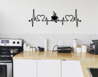 May include: Black metal wall art featuring a stylized heartbeat with two hearts and a coffee cup with steam rising from it. The art is mounted on a white wall above a kitchen counter with appliances and cabinets.