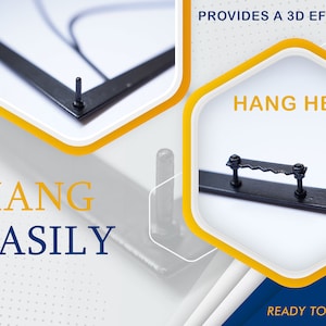 May include: Close-up of a black metal frame with two hanging options. The frame has a small metal hook on the back for hanging on a nail, and a larger metal bar with two screws for hanging on a hook. The text "HANG HERE" and "READY TO HANG" is visible on the image.