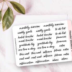 Puede incluir: Una hoja de pegatinas de encabezado con texto negro escrito a mano sobre un fondo blanco. Las pegatinas incluyen frases como "monthly overview", "weekly goals" y "habit tracker". La hoja tiene un borde rosa y el texto "Header Stickers" es visible.
