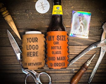 May include: A brown beer bottle with a yellow and blue label, and an orange leather koozie that says "ANY SIZE CAN, BOTTLE, GLASS, HAND MADE TO ORDER." A tan leather koozie says "YOUR LOGO HERE OR ANYWHERE." A trading card and tools are also present.