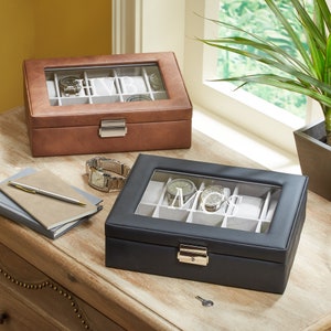 May include: Two watch boxes with glass lids. The box on the left is brown leather with the initials "HVB" engraved on the lid. The box on the right is black leather with the initials "MCS" engraved on the lid.