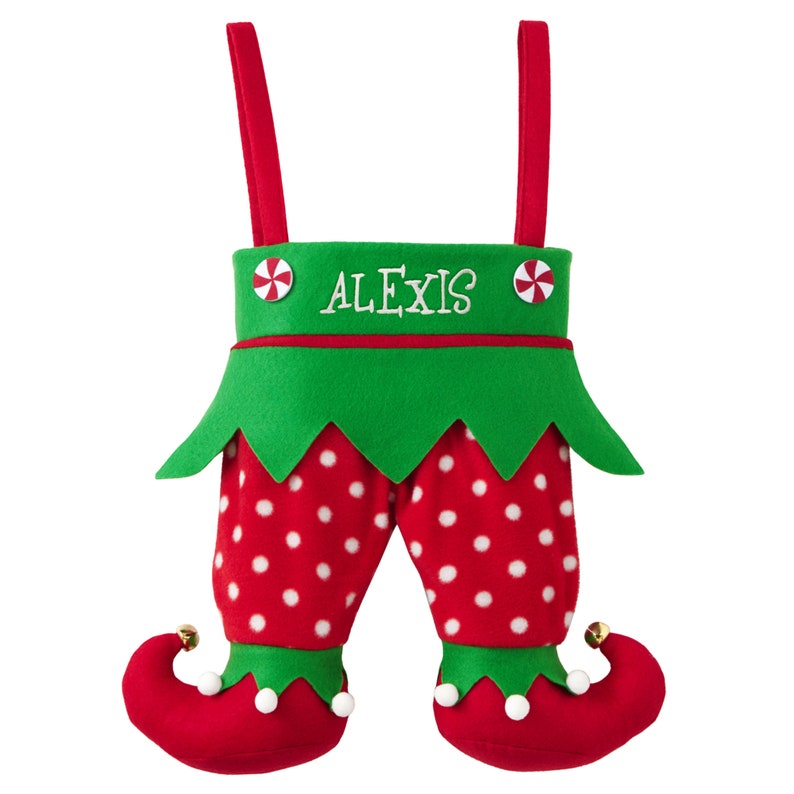 May include: A Christmas stocking shaped like elf legs. The red and white polka dot pants have green trim and red elf shoes with bells. The green top has the name "ALEXIS" embroidered in white. Red straps are attached to the top.