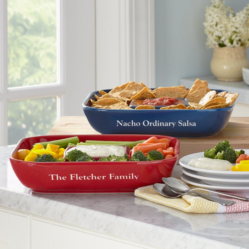 K&ouml;nnte beinhalten: Zwei Keramik-Servierplatten, eine rote und eine blaue, mit F&auml;chern f&uuml;r Dips und Snacks. Die rote Platte tr&auml;gt den Text "The Fletcher Family" und die blaue Platte tr&auml;gt den Text "Nacho Ordinary Salsa".