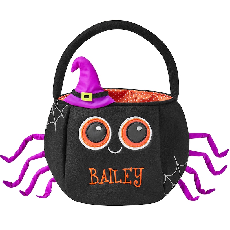 May include: Black Halloween-themed trick-or-treat bag shaped like a spider. The bag has a witch hat, spider legs, and the name "BAILEY" embroidered in orange. The bag has a black handle and a red polka dot interior.