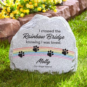 May include: A gray stone memorial with a rainbow and paw prints. The text reads "I crossed the Rainbow Bridge knowing I was loved. Molly Our Angel Above."