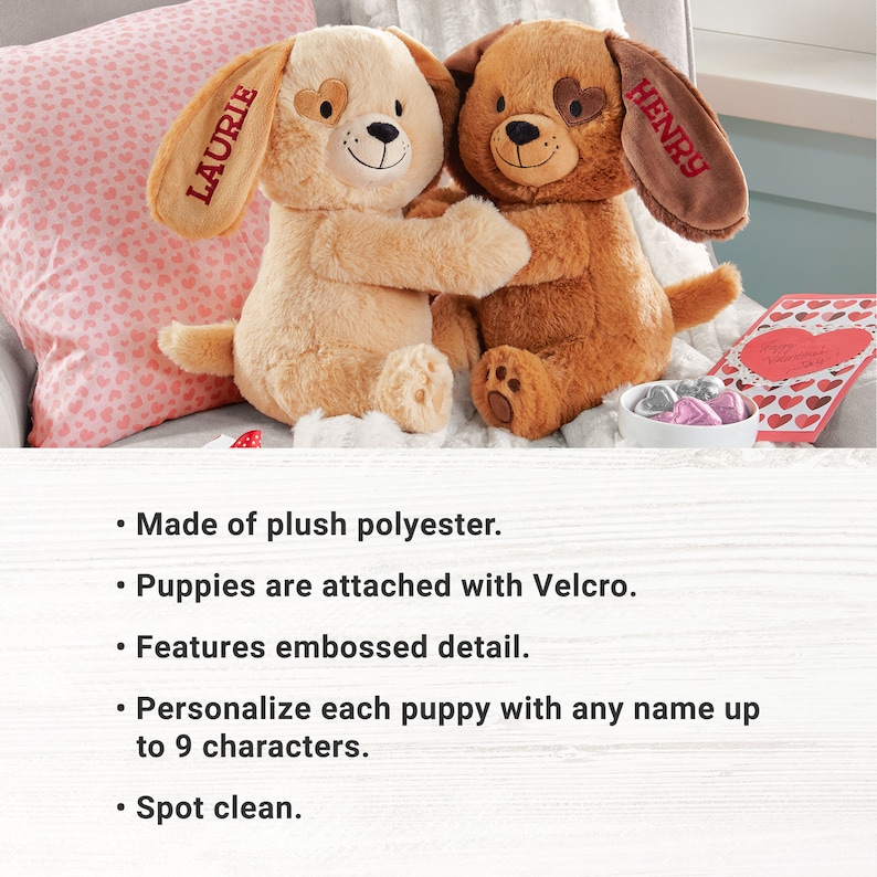 May include: Two plush brown and beige puppies with embroidered hearts on their chests are hugging. The puppies are attached with Velcro and have personalized names, "Laurie" and "Henry", embroidered on their ears.