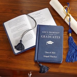 May include: A navy blue graduation gift set featuring a book titled "God's Promises for Graduates" with a tassel bookmark, a diploma scroll, and an open book. The book is personalized with the graduate's name and the year 2024.