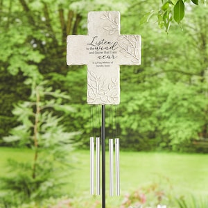 May include: A stone-coloured cross-shaped wind chime with the text "Listen to the wind and know that I am near" and "In Loving Memory of Dorothy Jones." The cross has leaf designs and silver chimes.