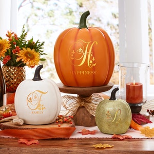 May include: Three decorative pumpkins with a gold glitter finish and a gold monogram on each. The pumpkins are labeled "Happiness", "Family", and "Love".