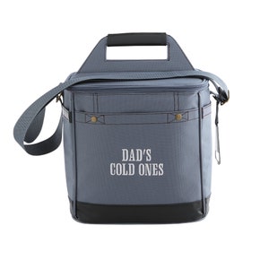 Pu&ograve; includere: Una borsa termica in tela grigia con una maniglia nera e un fondo nero. La borsa ha una parte superiore con cerniera e una tracolla. La parte anteriore della borsa ha il testo "DAD'S COLD ONES" ricamato in bianco.