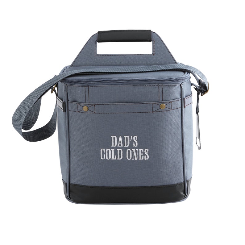 Pu&ograve; includere: Una borsa termica in tela grigia con una maniglia nera e un fondo nero. La borsa ha una parte superiore con cerniera e una tracolla. La parte anteriore della borsa ha il testo "DAD'S COLD ONES" ricamato in bianco.