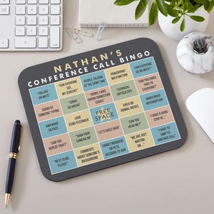 May include: A personalized conference call bingo game mousepad with a dark gray background. The text "NATHAN'S CONFERENCE CALL BINGO" is at the top. The bingo grid includes phrases like "You are on mute" and "Can you hear me?"