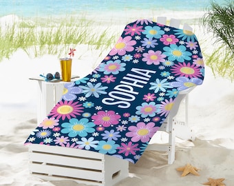 May include: A navy blue beach towel with a floral pattern in shades of pink, blue, and yellow. The towel has the name "Sophia" printed in white on it.