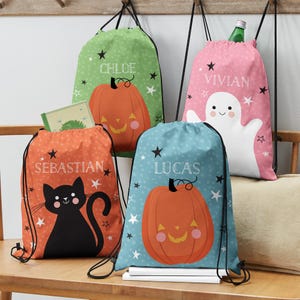 May include: Four colorful drawstring bags with Halloween themes. The bags feature a black cat, a ghost, a pumpkin, and a pumpkin with a smiling face. Each bag has a name on it: Sebastian, Lucas, Chloe, and Vivian.