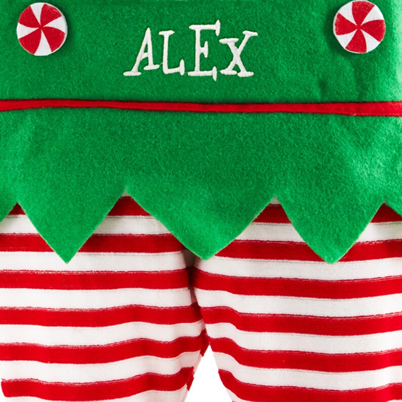 May include: A festive Christmas stocking featuring a green felt top with the name "ALEX" embroidered in white. The stocking has red and white striped legs and is adorned with peppermint candy accents.