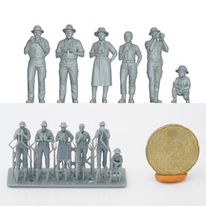 Può includere: Una collezione di figurine in miniatura non verniciate di persone, tra cui figure che tengono binocoli, macchine fotografiche e indossano cappelli. Le figure sono in varie pose ed è inclusa una moneta da 2 euro per la scala.
