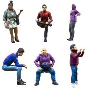 Op de afbeelding: Zes figuren van mensen in verschillende poses, gekleed in verschillende kleuren kleding. De figuren zijn gemaakt van plastic en ongeveer 3,8 cm hoog.