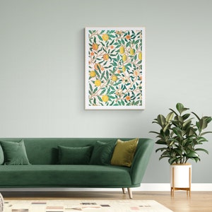 May include: A green velvet sofa with three cushions, one green, one white and one gold, sits in front of a white wall with a framed print of a floral pattern with yellow and orange flowers and leaves. A potted plant with green leaves is on the right side of the sofa.