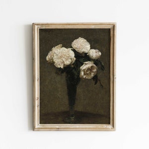 May include: A framed painting depicting a bouquet of white roses in a clear glass vase. The roses are arranged in a loose, natural style, and the vase is placed on a dark brown table. The background is a dark green colour.