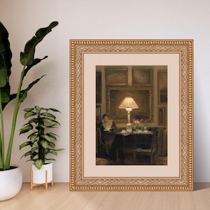 Vintage art print of a cozy interior scene with a glowing lamp, woman reading by a table, surrounded by framed paintings, flowers, and tea cups