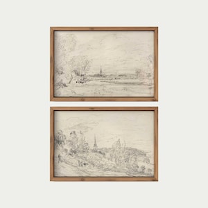 May include: Two framed pencil sketches depicting a landscape with trees, buildings, and water. The artwork uses a neutral colour palette, highlighting the details of the scenery. The frames are made of light brown wood.