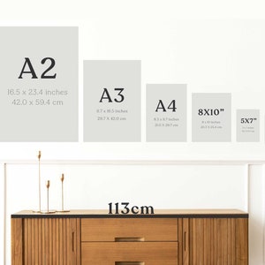 Peut inclure: Un mur blanc avec un meuble en bois en dessous. Le mur pr&eacute;sente cinq cadres en papier de diff&eacute;rentes tailles avec les dimensions de chaque cadre indiqu&eacute;es en pouces et en centim&egrave;tres. Les cadres sont &eacute;tiquet&eacute;s A2, A3, A4, 8x10", 5x7" et 4x6". Le texte "113cm" est &eacute;crit sous les cadres.