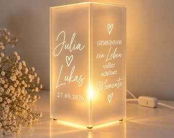 May include: A rectangular frosted glass lamp emitting a warm glow, featuring the names Julia and Lukas, the date 27.09.2026, heart icons, and the German text GEMEINSAM ein Leben voller schöner Momente printed on the front surface.
