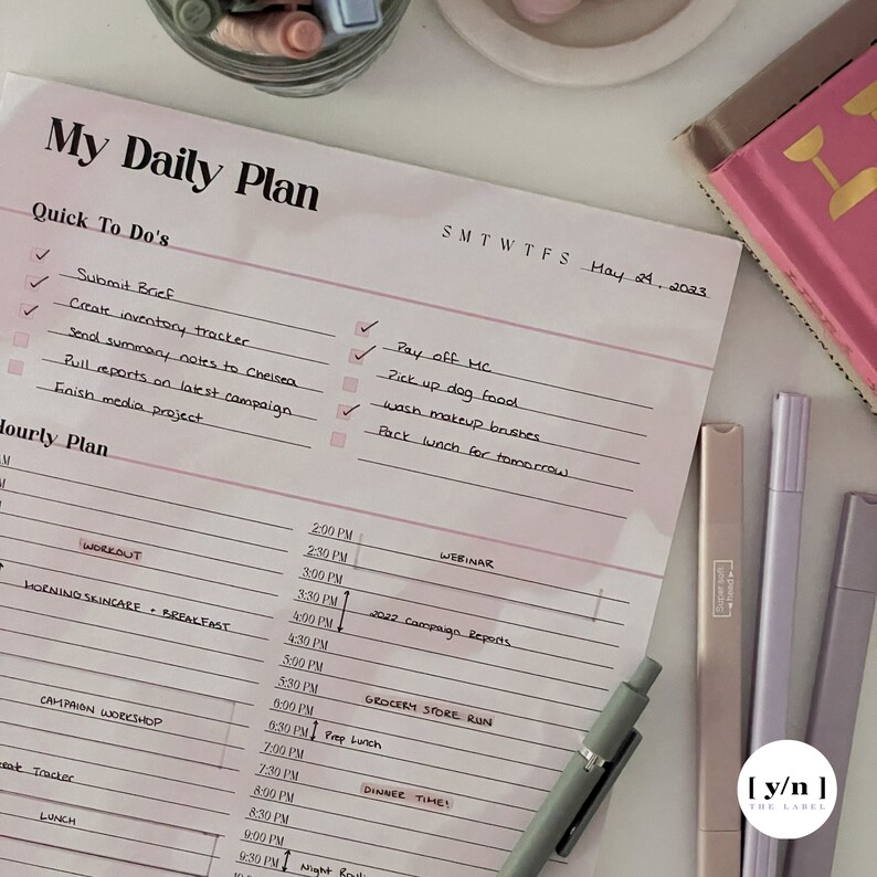 May include: A pink and white daily planner with a checklist of tasks for the day. The planner includes a section for "Quick To Do's" and "Hourly Plan". The date is May 24, 2023.