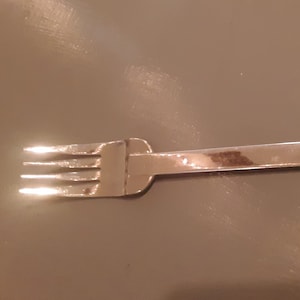 Puede incluir: Un tenedor de plata con cuatro dientes.