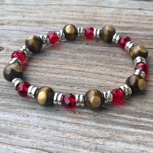 Peut inclure: Un bracelet en perles brunes et dorées avec des perles de verre rouges et des entretoises argentées.