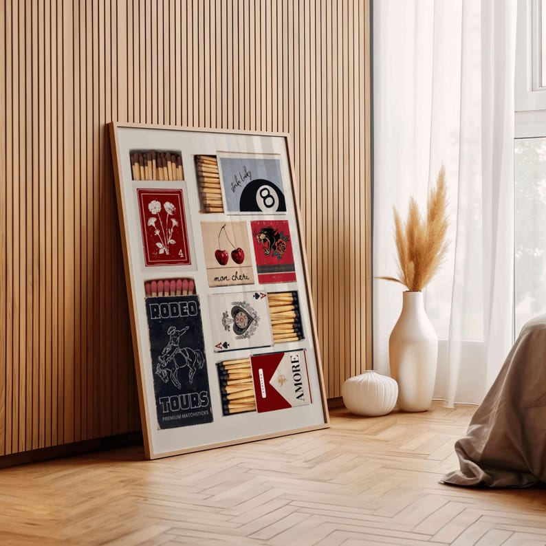 May include: A framed collage of matchbox labels with various designs, including cherries, a cowboy on a horse, a playing card, a pool ball, and flowers. The labels are in red, blue, and white with black text.