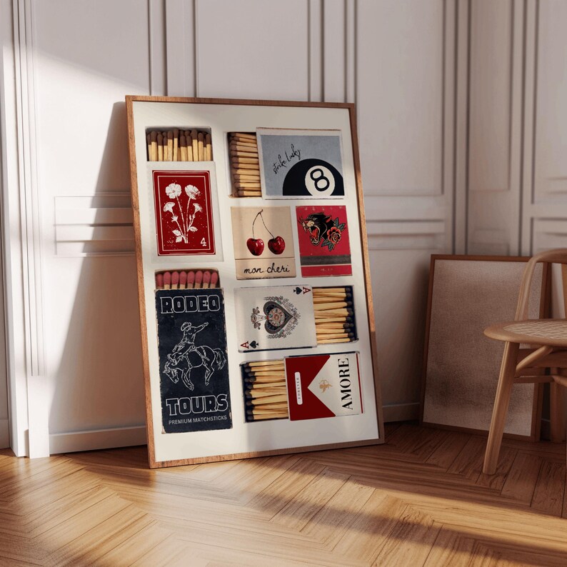 May include: A framed collage of matchboxes with various designs, including a red box with a flower, a red box with cherries, a red box with a panther, a blue box with a cowboy riding a horse, a blue box with a playing card, and a red box with the word "AMORE".