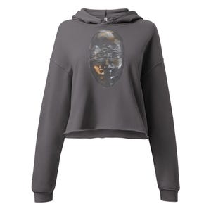 May include: A charcoal grey cropped hoodie featuring long sleeves and a hood with drawstrings. The centre of the chest displays a graphic of a faceted, crystalline oval shape with a metallic, reflective surface and horizontal rippled lines.