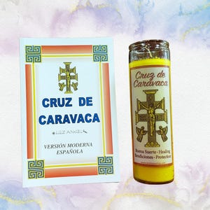 May include: A yellow candle with a gold image of the Holy Cross of Caravaca. The candle has the text "Cruz de Caravaca" and "Buena Suerte - Healing Bendiciones - Protection" printed on it. The candle is next to a book with the title "Cruz de Caravaca" and the text "Versión Moderna Española".