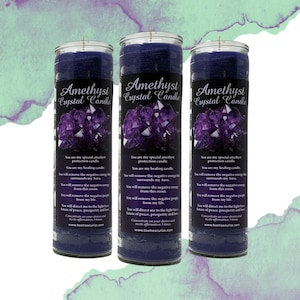 May include: Three dark purple Amethyst Crystal Candles with labels featuring amethyst crystal graphics and text. The candles are cylindrical and have a wick at the top. The labels include text about healing and removing negative energy.