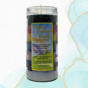 May include: A multi-colored Abre Camino Road Opener candle in a clear glass jar. The candle has layers of dark green, red, yellow, blue, and gray. Text on the label reads "Abre Camino Road Opener". A wick extends from the top.