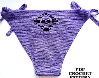Könnte beinhalten: Ein violettes Häkel-Bikiniunterteil mit einem schädelförmigen Ausschnitt in der Mitte und seitlichen Bindebändern. Der Text PDF CROCHET PATTERN INSTANT DOWNLOAD ist unten rechts im Bild in Schwarz aufgedruckt.