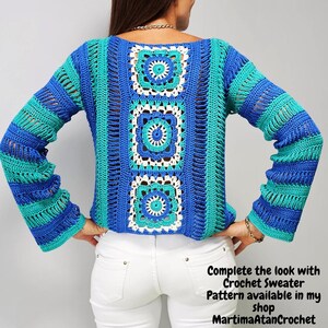 May include: A long-sleeved crochet sweater featuring a central vertical panel of three square motifs in blue, turquoise, and white. The sleeves and sides are constructed with horizontal stripes of blue and turquoise yarn in an openwork stitch.
