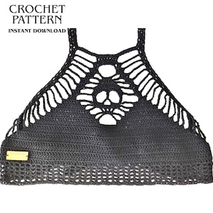 Puede incluir: Un top halter de ganchillo negro con un motivo central de calavera con detalles calados, tirantes finos y una etiqueta rectangular de color tostado en la parte inferior izquierda. El texto CROCHET PATTERN INSTANT DOWNLOAD es visible arriba.