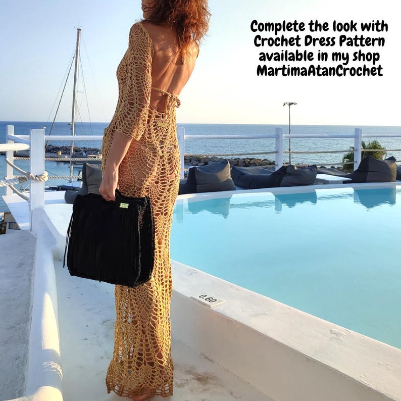 May include: A floor-length beige crochet dress with an open back and long sleeves, featuring a complex openwork pattern. The dress is paired with a black fringed handbag. Text on the image reads: Complete the look with Crochet Dress Pattern available in my shop MartimaAtanCrochet.