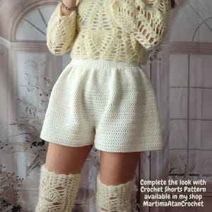 May include: A pale yellow long-sleeved crochet top with an openwork pattern, paired with solid white crochet shorts featuring a high elasticized waistband. The text reads: Complete the look with Crochet Shorts Pattern available in my shop MartimaAtanCrochet.