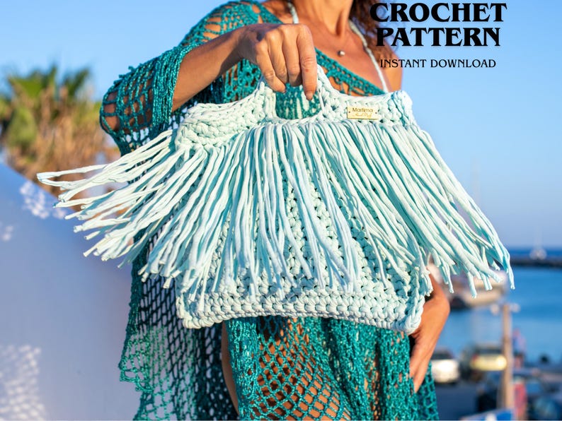 May include: A light blue crochet handbag featuring a dense fringe design on the front, two integrated handles, and a small rectangular label. The text CROCHET PATTERN INSTANT DOWNLOAD is visible in the upper right corner of the image.