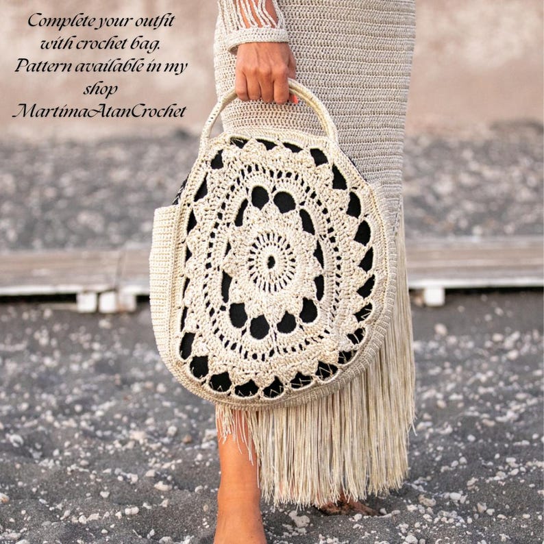 May include: A round beige crochet bag with a detailed circular lace pattern and a solid black interior lining. The bag features a matching beige crochet handle and long fringe trim along the bottom edge. Text reads: Complete your outfit with crochet bag. Pattern available in my shop MartimaAtanCrochet.
