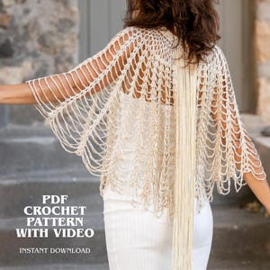 Puede incluir: Un chal de ganchillo color crema con un patrón de red abierto y largos flecos colgantes. La prenda se lleva sobre una parte superior blanca acanalada. El texto en la imagen dice: PDF CROCHET PATTERN WITH VIDEO INSTANT DOWNLOAD.