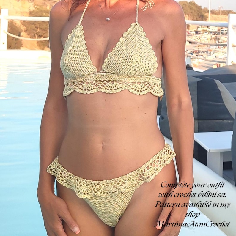 May include: A pale yellow crochet bikini set featuring a triangle top with scalloped edges and matching bottoms with a ruffled trim. The text on the image reads: Complete your outfit with crochet bikini set. Pattern available in my shop MartimaAtanCrochet.