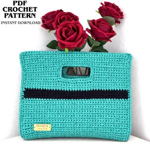Könnte beinhalten: Eine rechteckige, türkisfarbene Häkeltasche mit einem horizontalen schwarzen Streifen in der Mitte, einem rechteckigen Griffausschnitt und einem kleinen goldenen Etikett mit dem Text Martima Hand Made. Text lautet PDF CROCHET PATTERN.