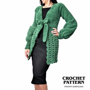 Peut inclure: Un cardigan vert en crochet à manches longues, avec une fermeture à nouer à la taille. Le cardigan a un aspect texturé et moelleux et présente un bord festonné. L'image comprend le texte "CROCHET PATTERN" et "INSTANT DOWNLOAD".