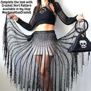 Puede incluir: Un top corto de ganchillo negro con mangas largas y una falda de ganchillo a juego con patr&oacute;n abierto y largos flecos drapeados. Un bolso negro con forma de pir&aacute;mide, asa circular y gr&aacute;fico de calavera blanca. Texto: Complete the look with Crochet Skirt Pattern available in my shop MartimaAtanCrochet.