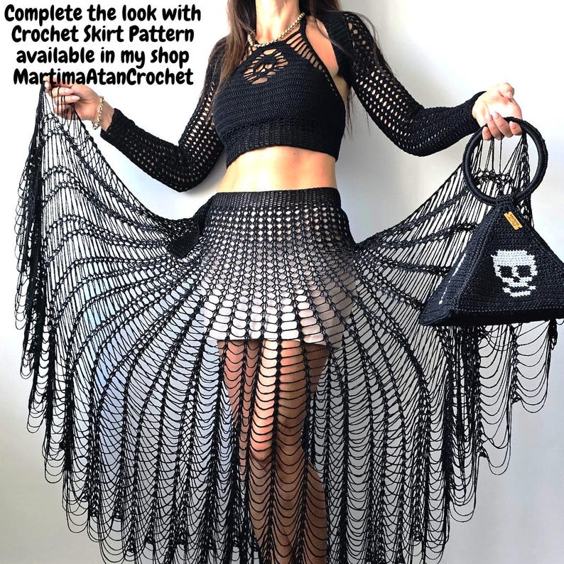 Puede incluir: Un top corto de ganchillo negro con mangas largas y una falda de ganchillo a juego con patr&oacute;n abierto y largos flecos drapeados. Un bolso negro con forma de pir&aacute;mide, asa circular y gr&aacute;fico de calavera blanca. Texto: Complete the look with Crochet Skirt Pattern available in my shop MartimaAtanCrochet.